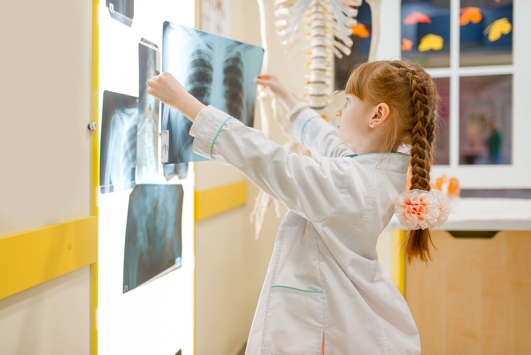 Little girl in uniform looks at the x-ray, doctor